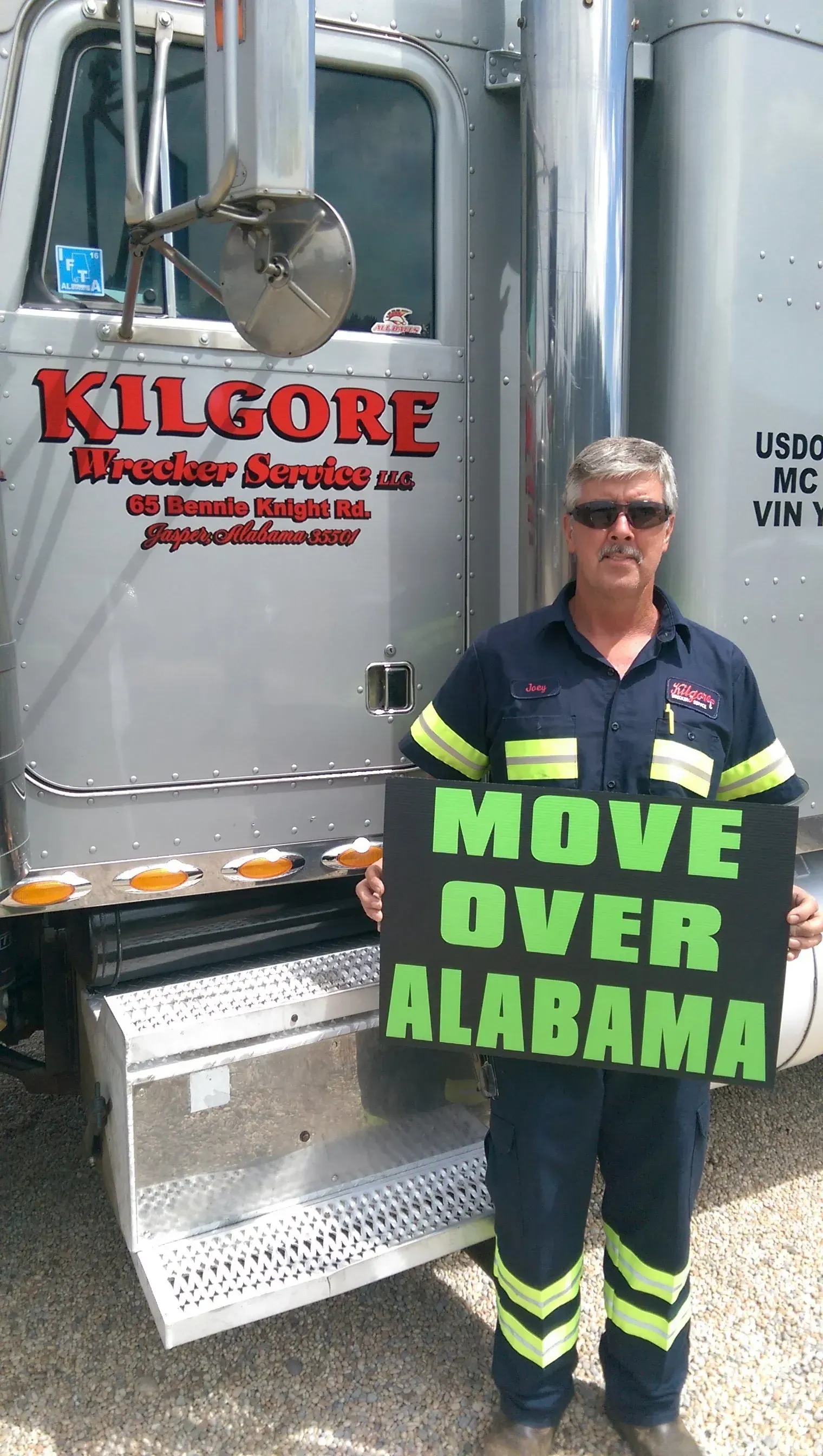 A man is holding a sign that says `` move over alabama '' in front of a truck.