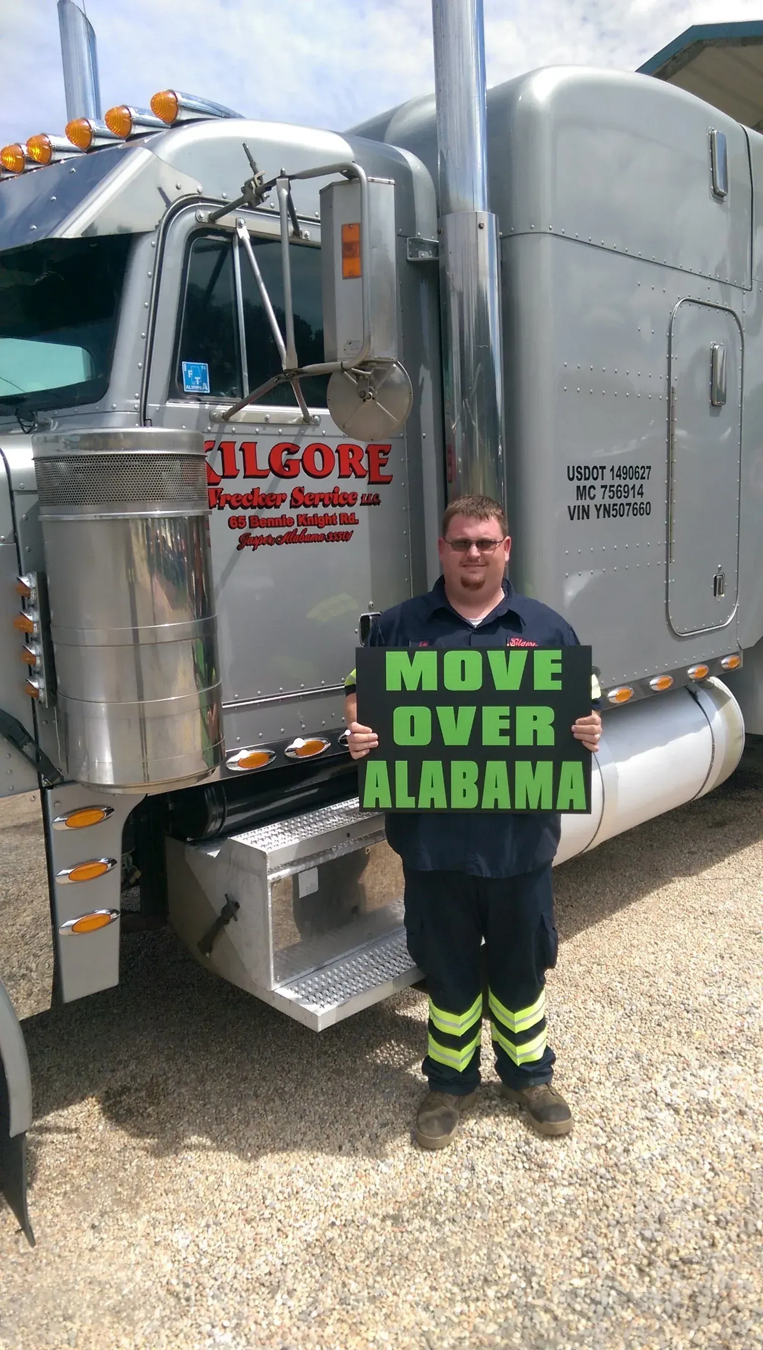 A man is standing in front of a grey truck.
