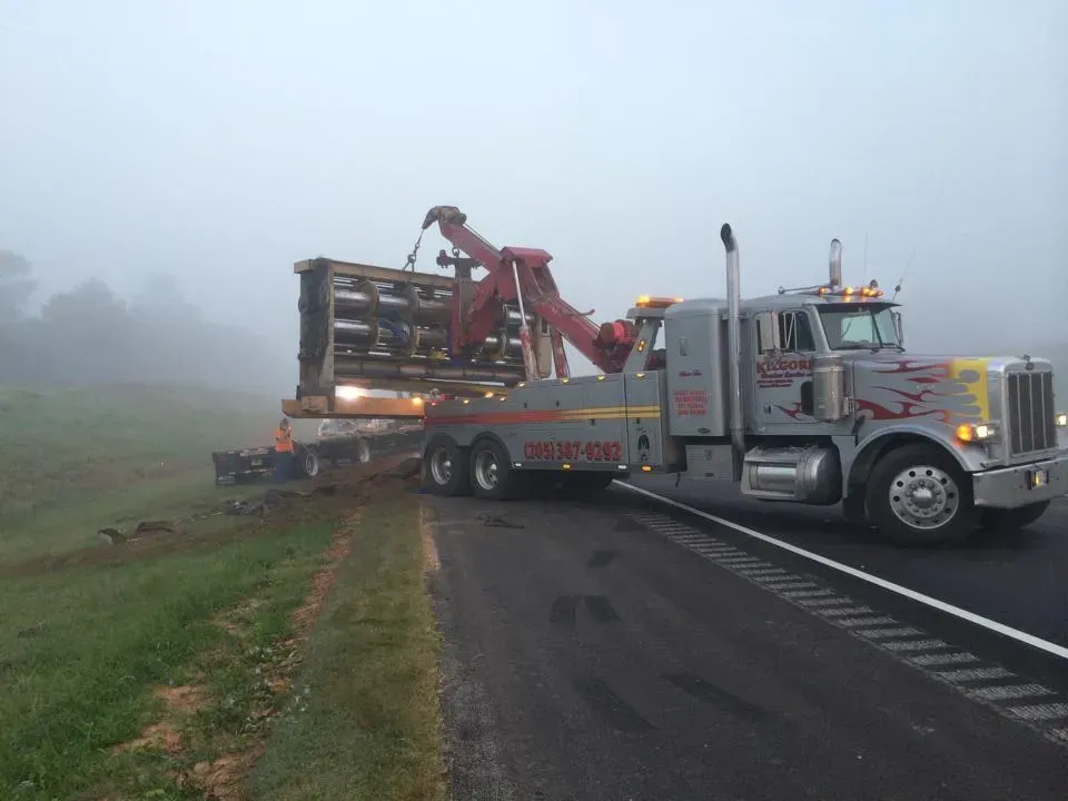 A tow truck is driving down a foggy highway.