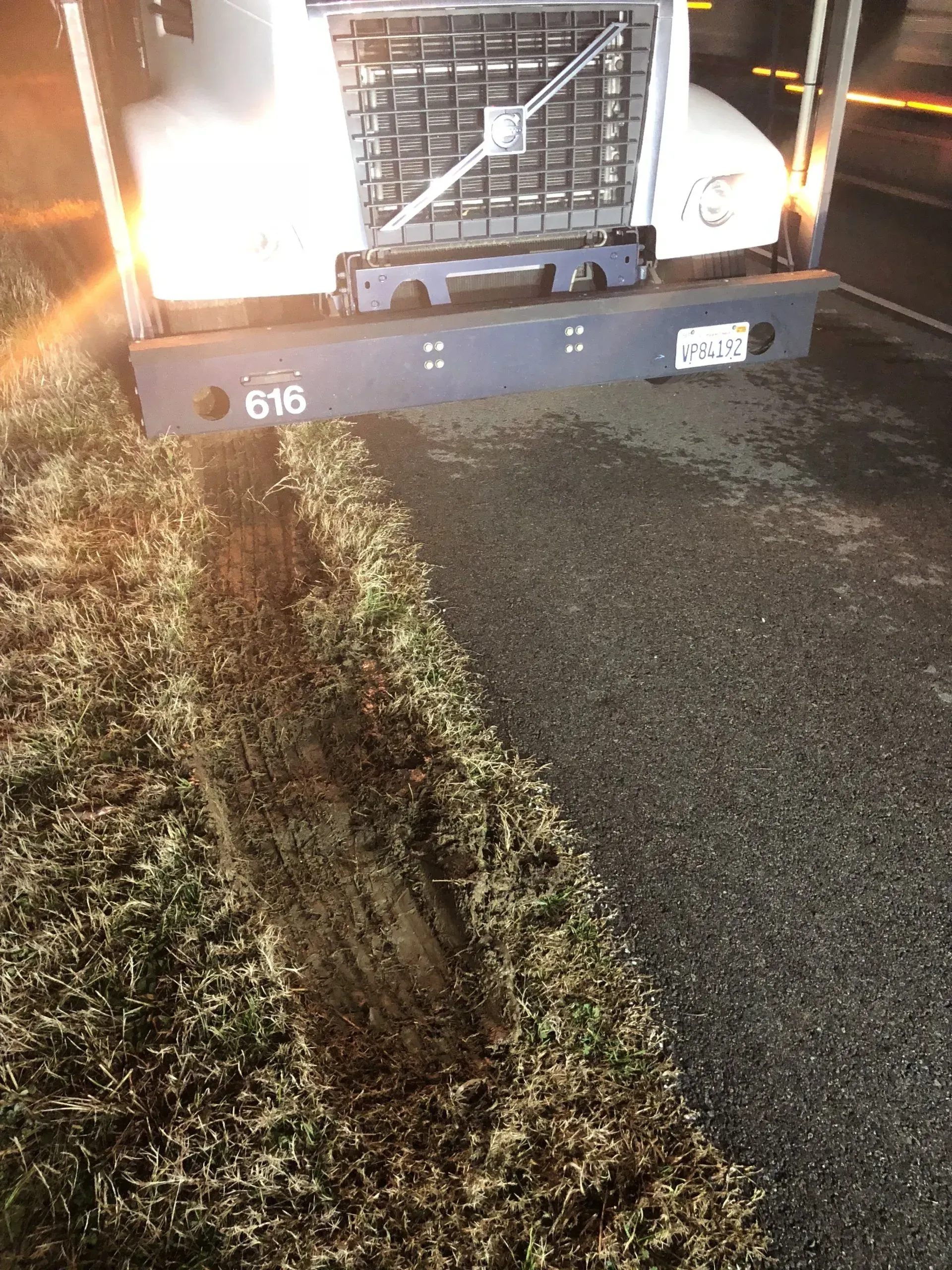 A truck is parked on the side of the road next to a grassy area.