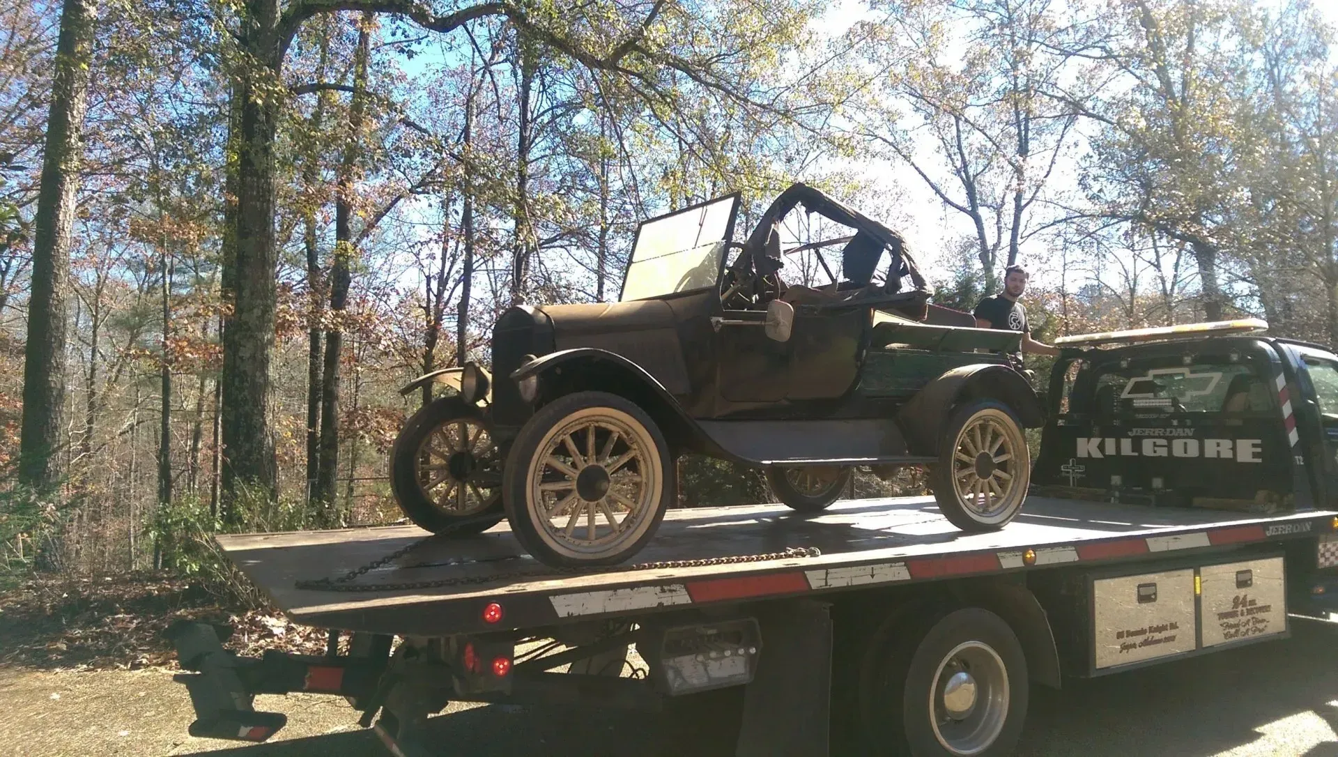 An old car is sitting on top of a flatbed tow truck.