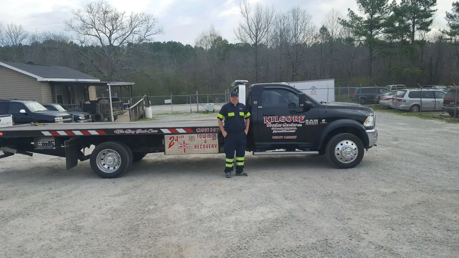 A man is standing in front of a tow truck.