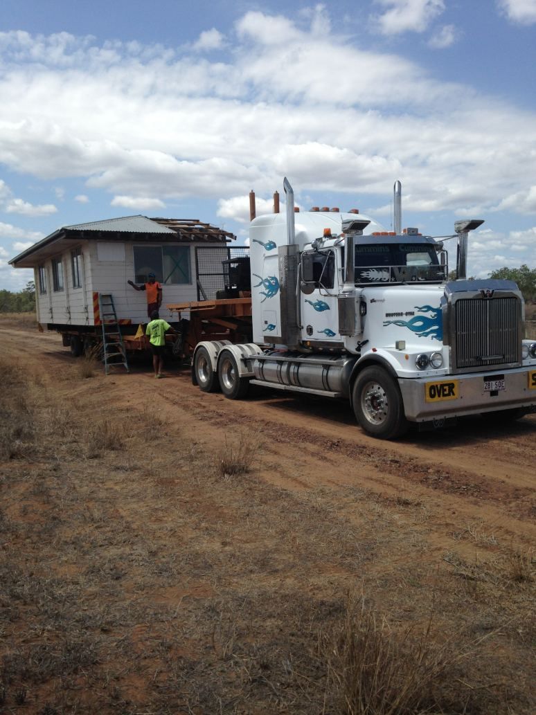 A Semi Truck Is Carrying a House Down a Dirt Road — Conan The House Lifter In Townsville, QLD