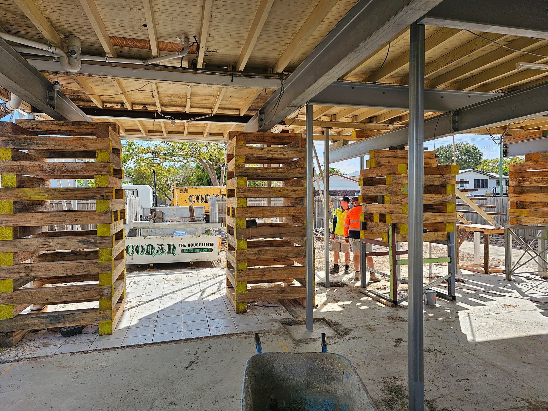 A Tree Stump Is Sitting in The Dirt Next to A Wheelbarrow — Conan The House Lifter In Townsville, QLD