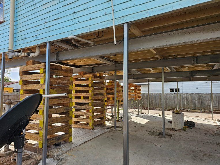 A Building Under Construction with Wooden Pallets and Pipes — Conan The House Lifter In Townsville, QLD