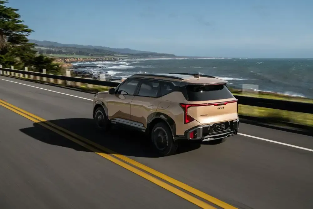 Kia Seltos 2027 circulando por una carretera costera junto al océano.
