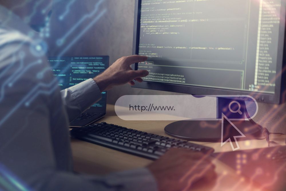 Person coding at a desk with multiple monitors, with a security icon overlay and web address bar visible
