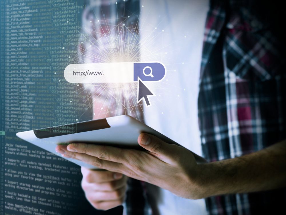 Person holding a tablet and stylus with a search bar and code background, suggesting online search or data access
