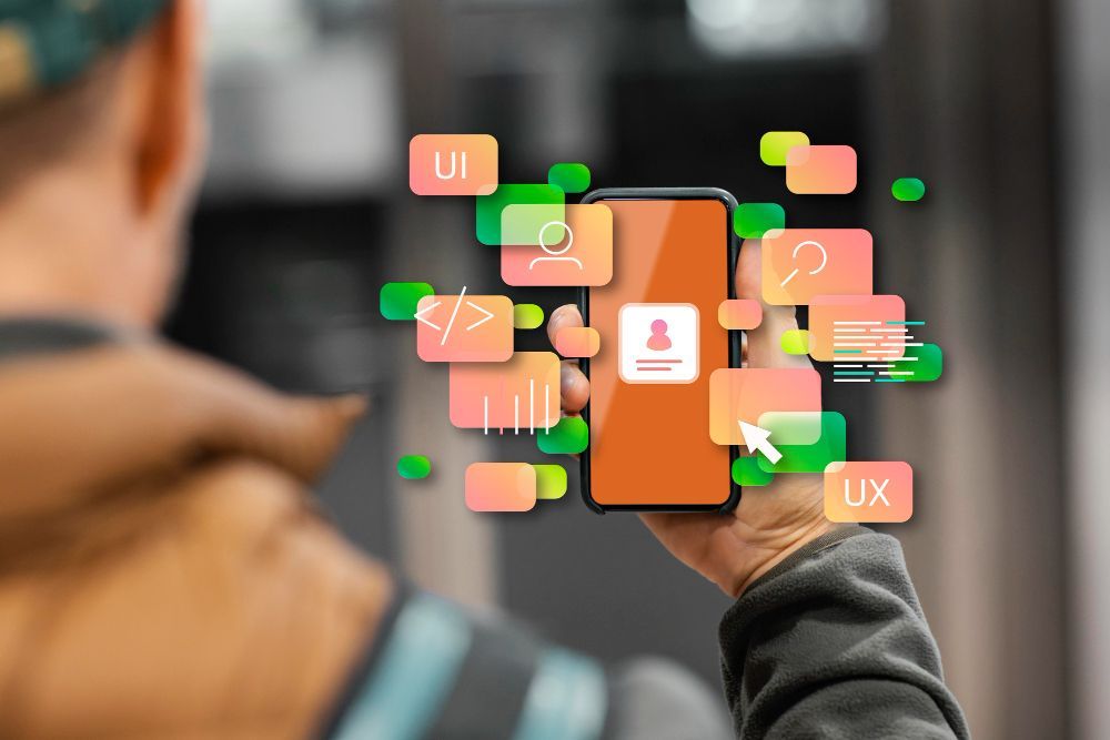 Hand holding a smartphone with colorful UI icons floating around it in a blurred background