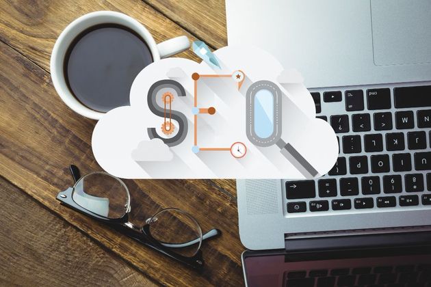SEO concept with cloud icon, laptop, coffee cup, and glasses on a wooden desk