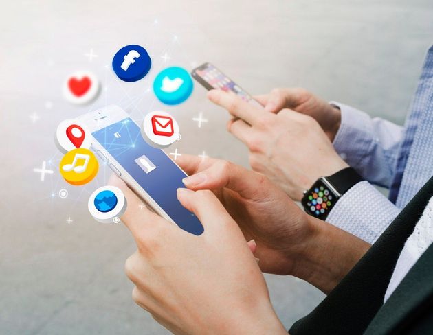Hands using smartphones with floating social media notification icons around them.