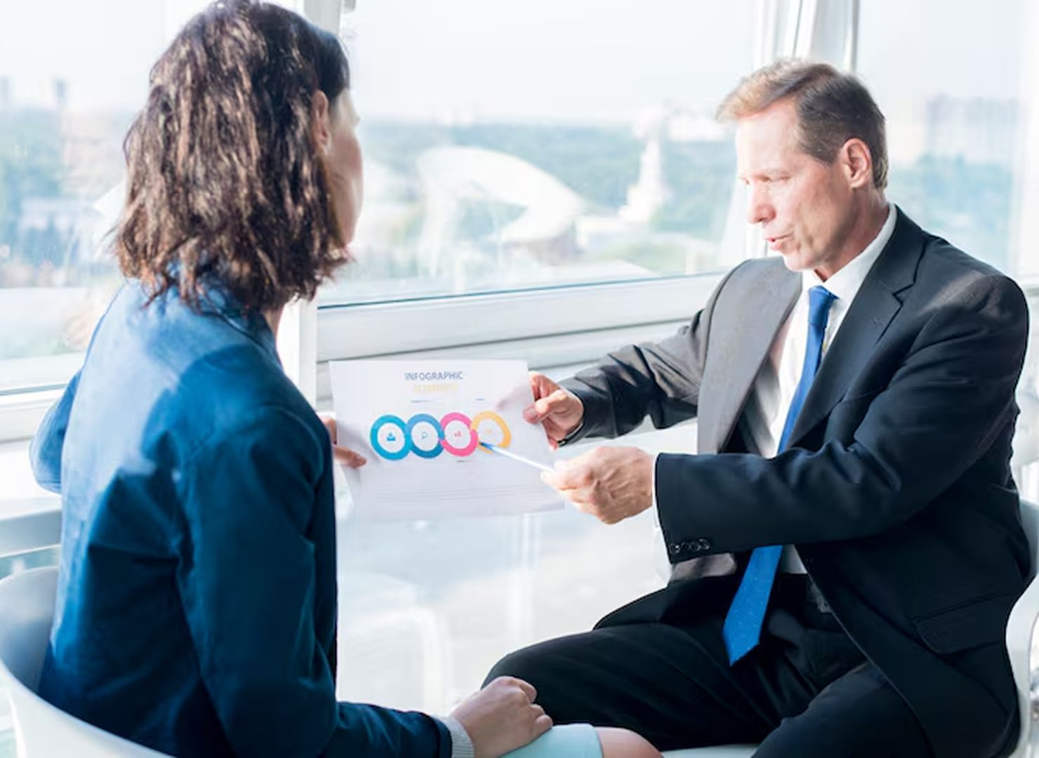 Two businesspeople reviewing a colorful chart in a bright office meeting room