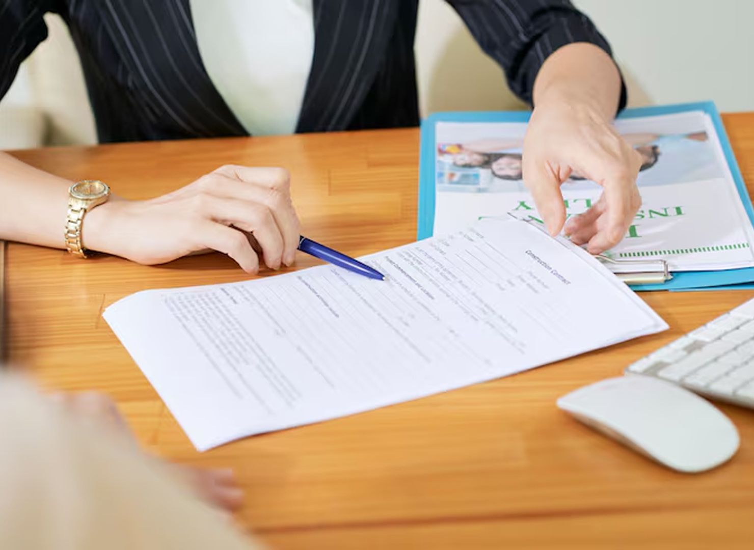 Hands reviewing a form on a wooden desk with a pen and clipboard nearby.