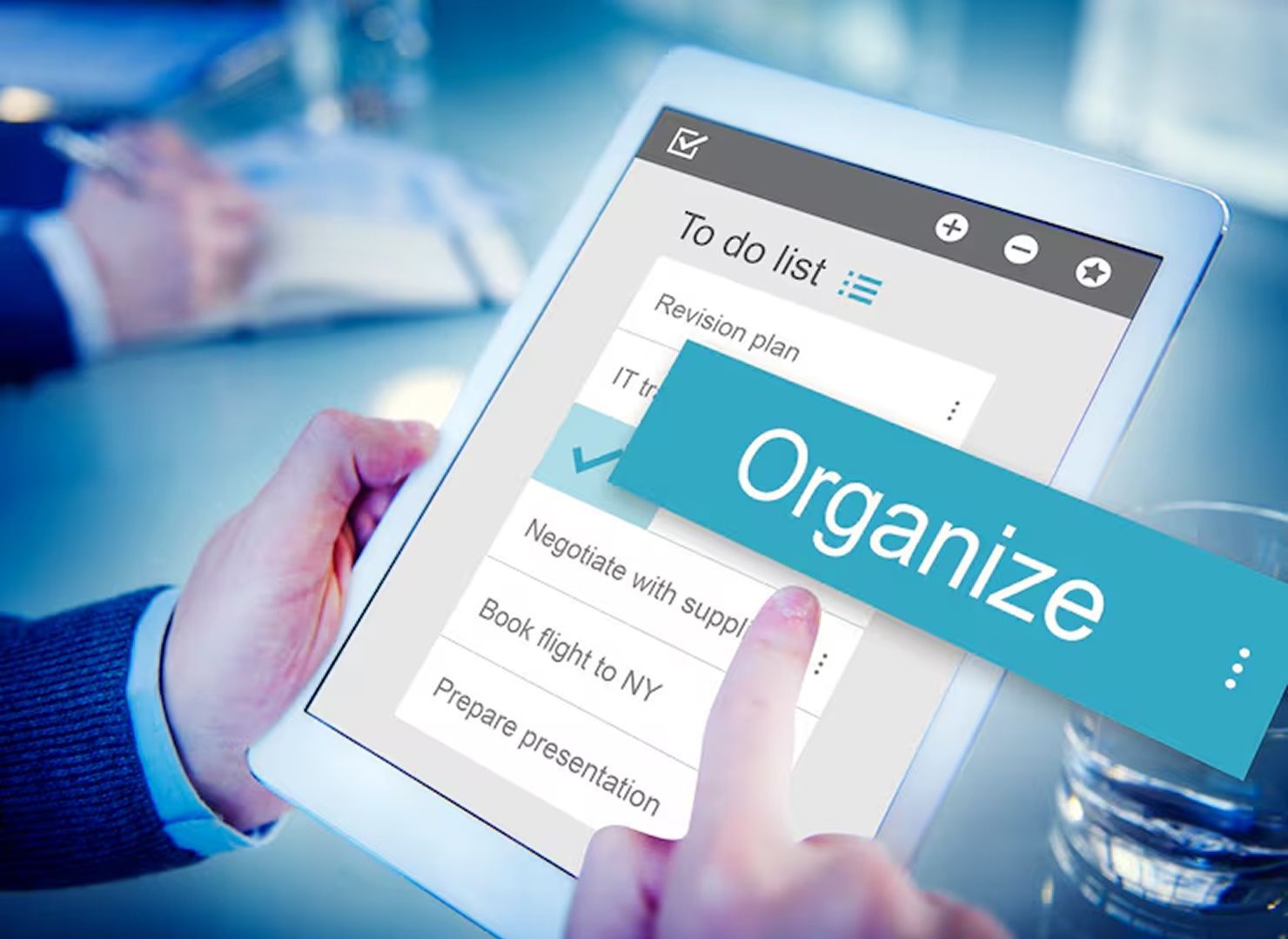 Hand holding a tablet showing a to-do list with a blue “Organize” label overlaying it