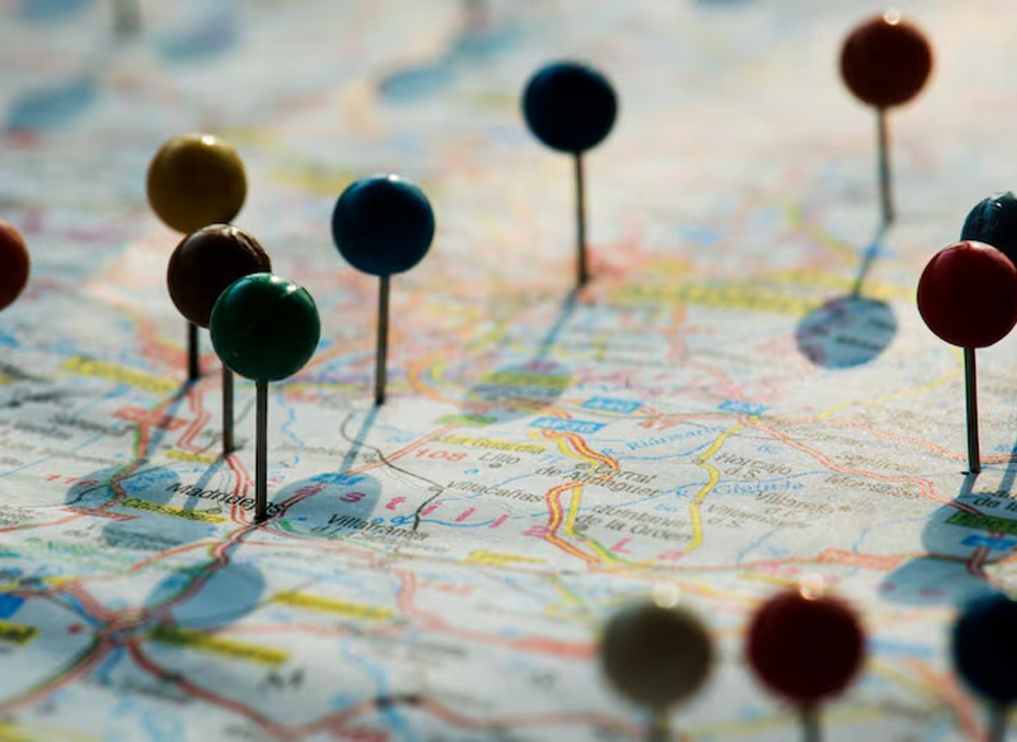 Colored push pins marking locations on a road map