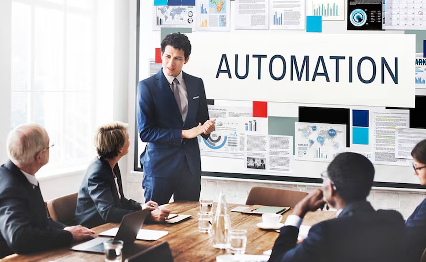 Business meeting on automation strategy, with presenter pointing at a screen labeled “AUTOMATION” in a conference room