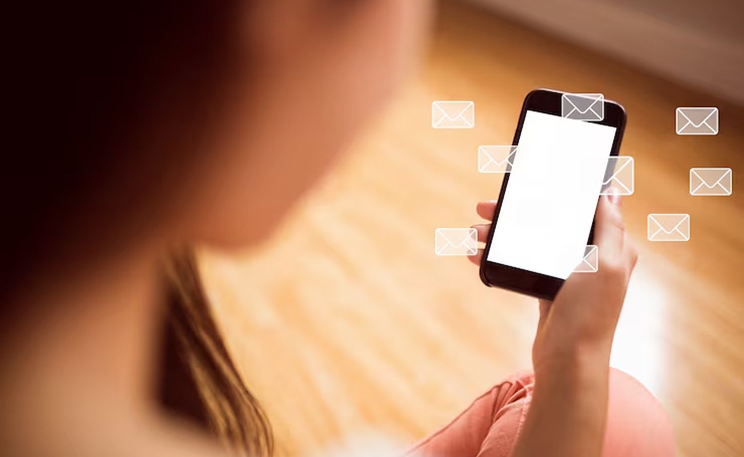 Person holding a smartphone with a bright screen and messaging icons floating around it.
