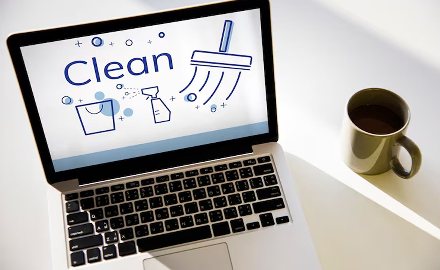 Laptop with a “Clean” screen graphic and coffee mug on a desk.