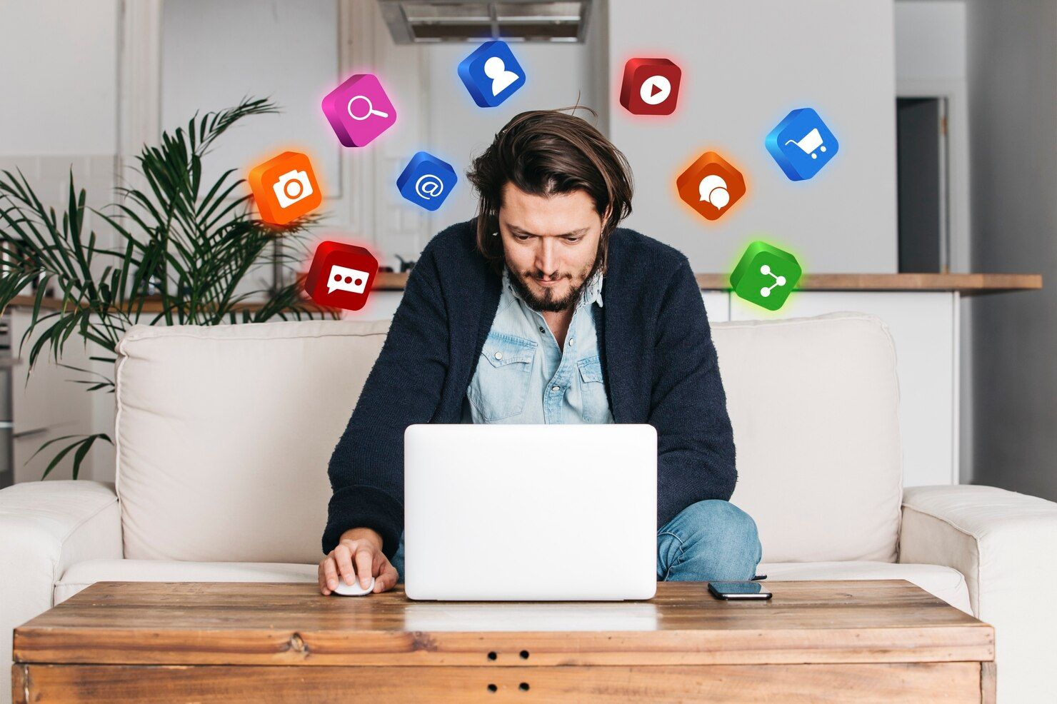 Man using a laptop on a couch, surrounded by colorful app icons floating around him