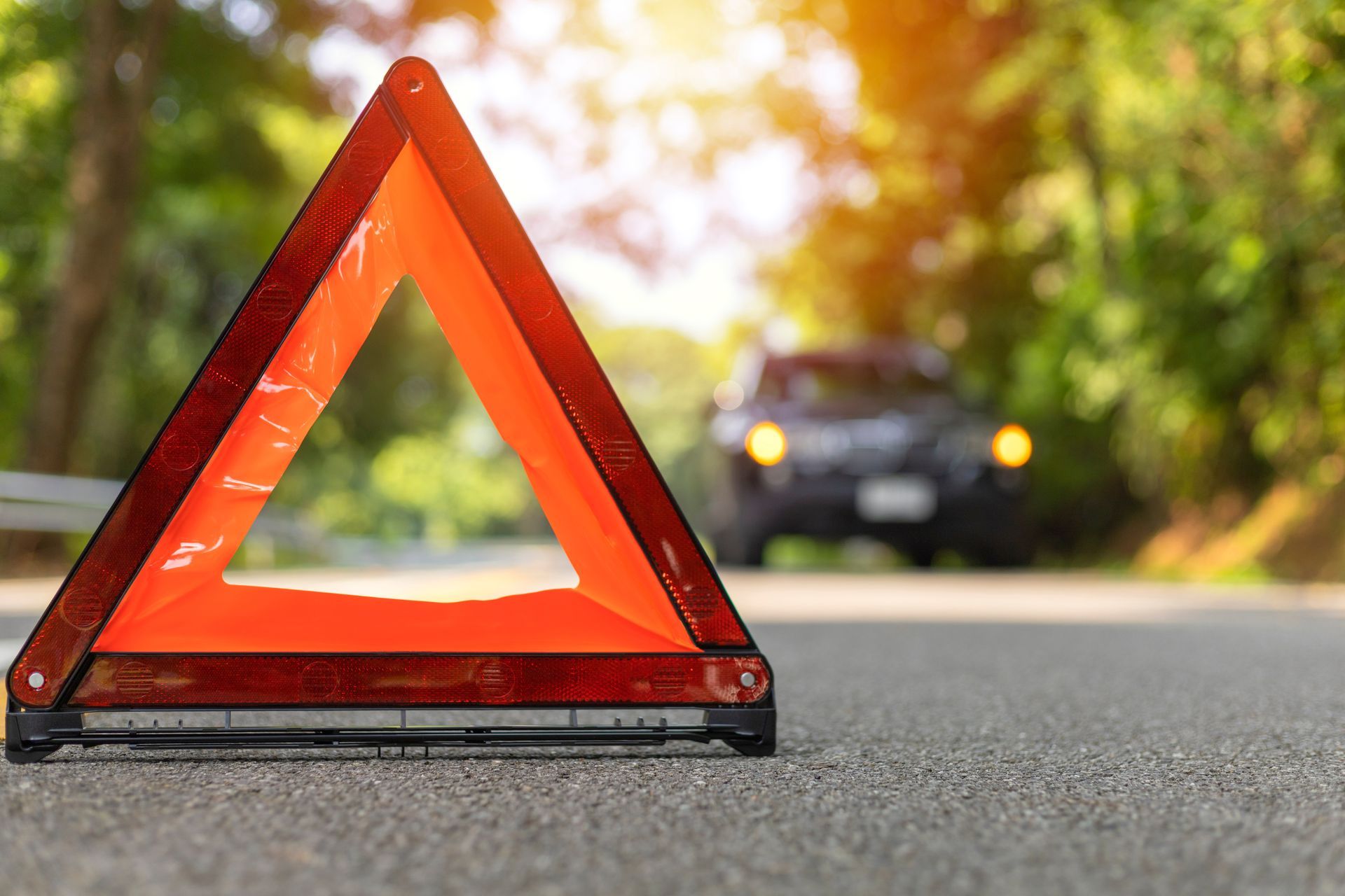 Emergency warning triangle on Arizona road after car breakdown or accident with vehicle in background
