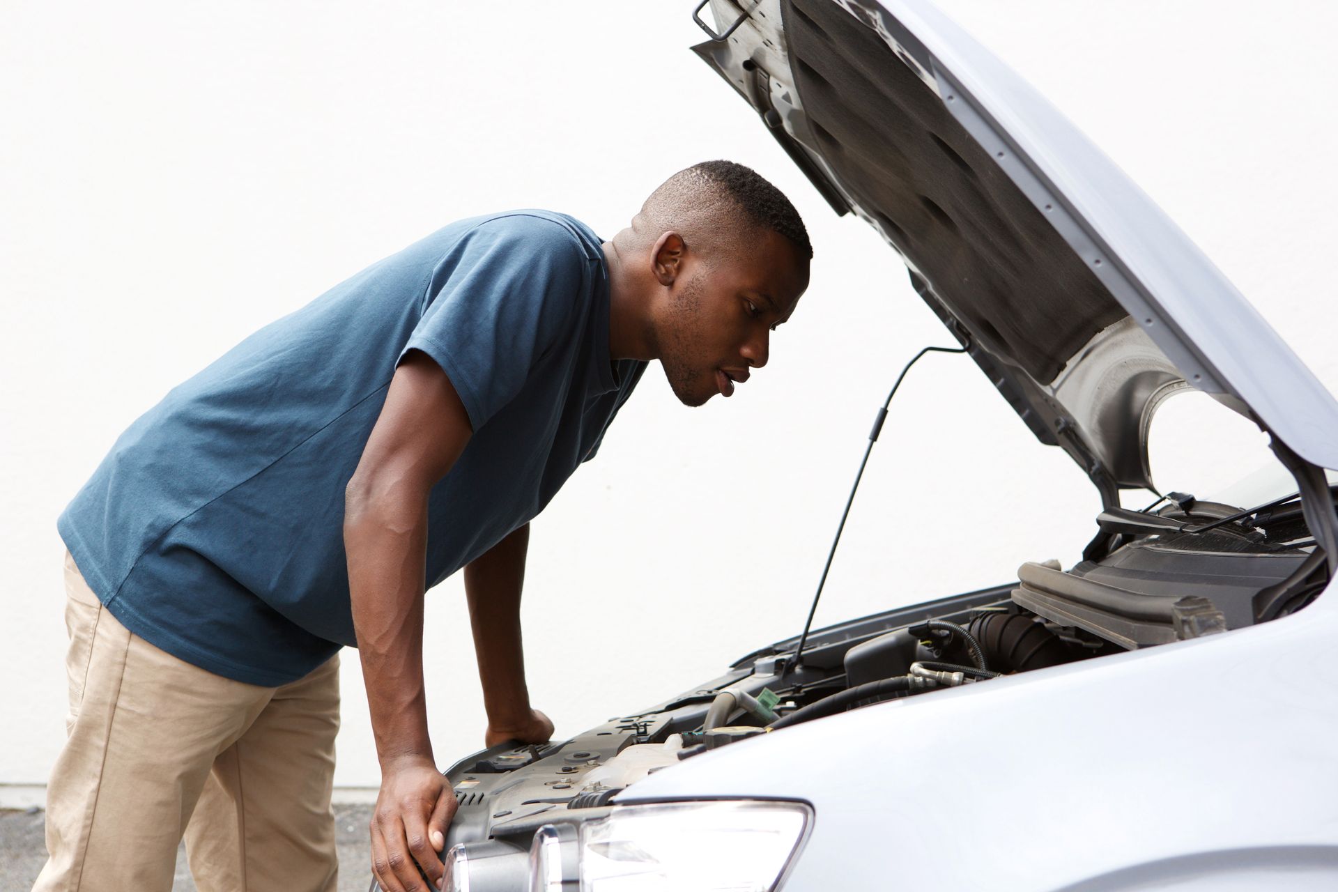 Driver checking car engine after breakdown on Arizona roadside, vehicle safety inspection scene
