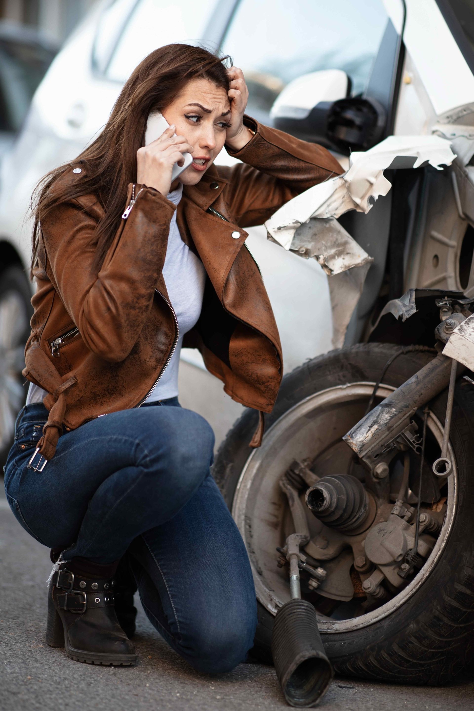 A female in distress while kneeling beside her vehicle after an automobile accident trying to call for help on a cell phone. Clicking this picture takes you to the Auto Accidents.