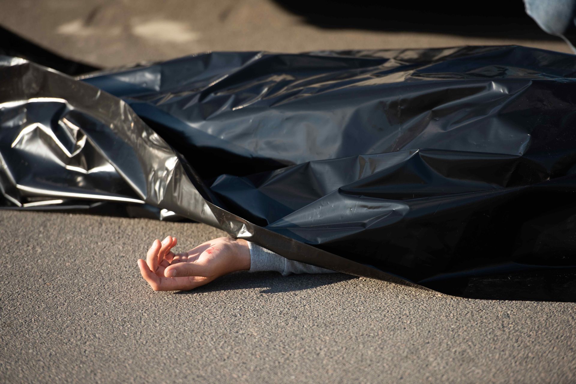 A picture of a person lying on the street, covered in a black cover presuming the time of death. This is for the section Death by Accidents.