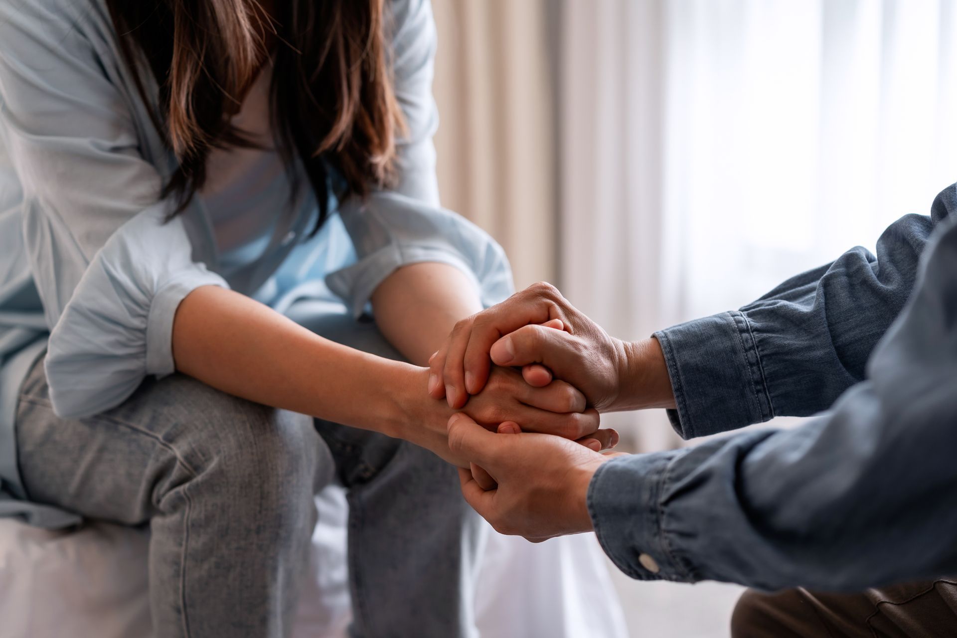Two people holding hands during a supportive conversation, symbolizing emotional support, counseling