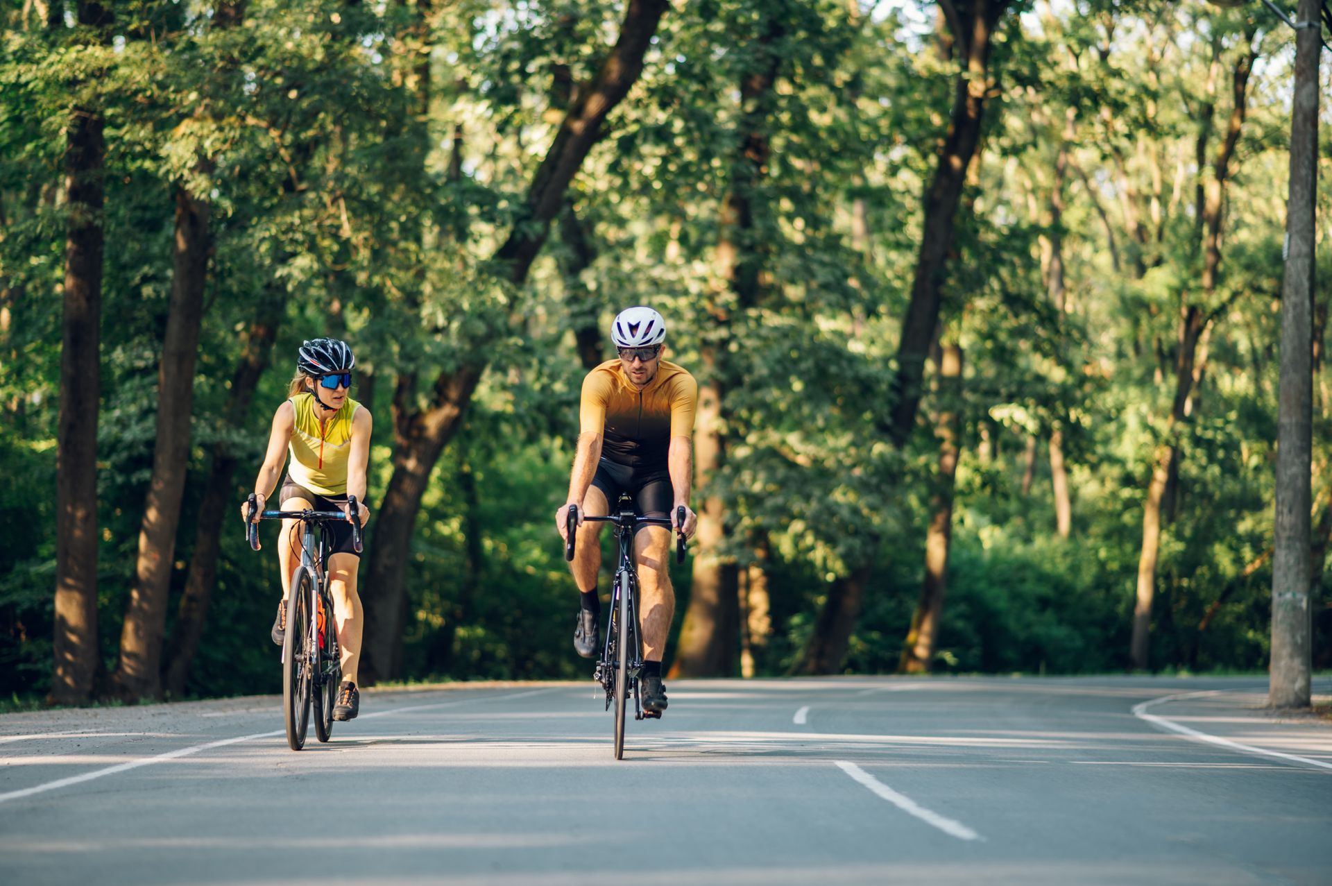 Two cyclists wearing helmets riding bicycles on roadway, promoting bike safety and accident awareness