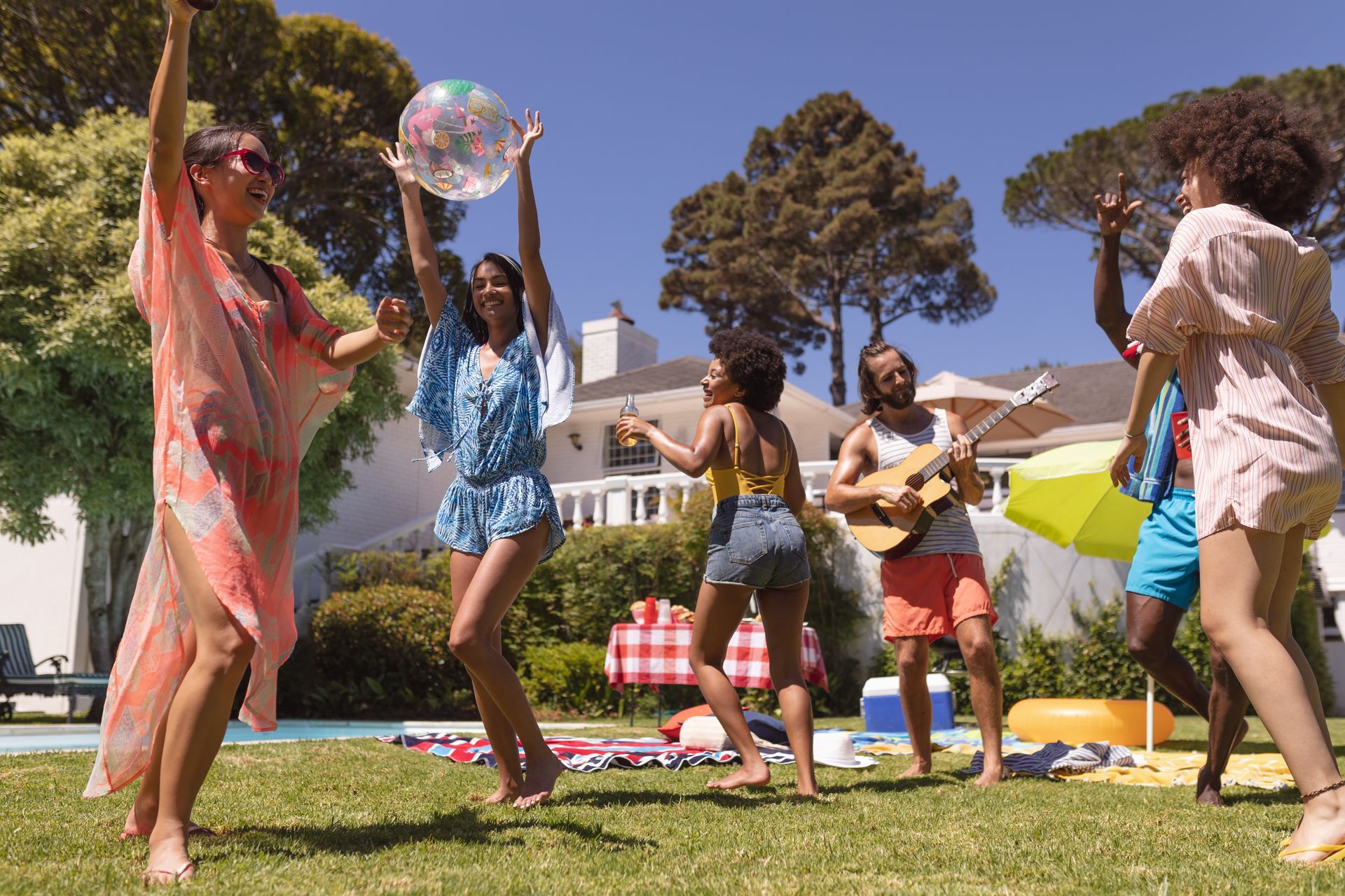 Group of friends dancing and enjoying outdoor summer party gathering in sunny weather