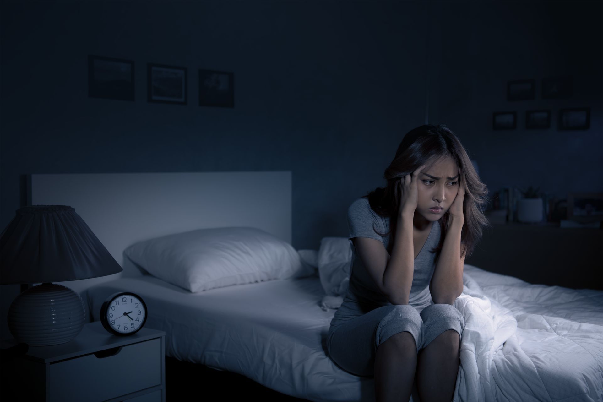 Woman sitting alone on a bed at night appearing distressed, illustrating depression, anxiety, and emotional struggles following a traumatic event.