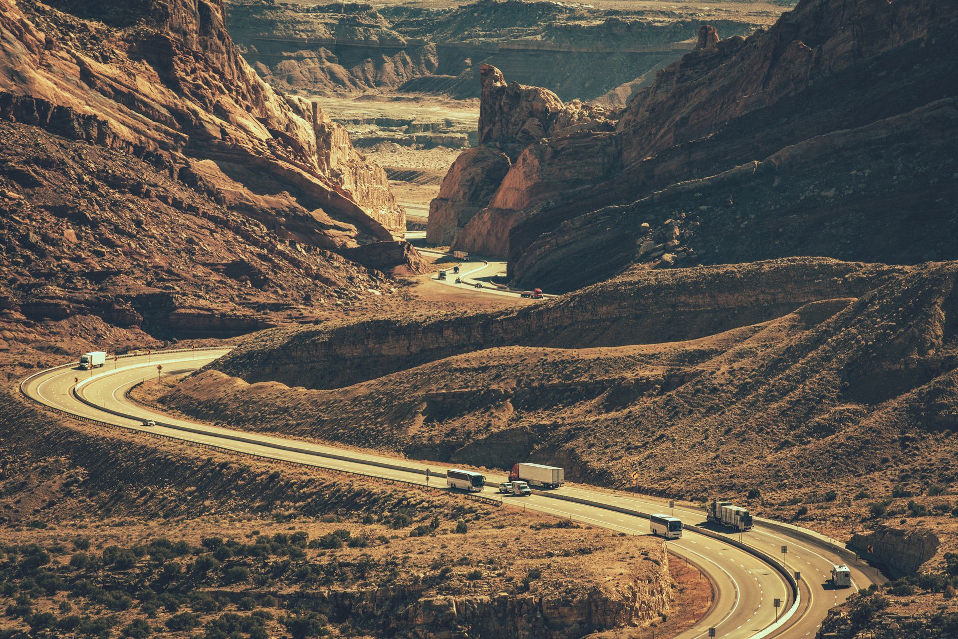 Winding Arizona desert highway with vehicles driving through canyon landscape, long distance travel route