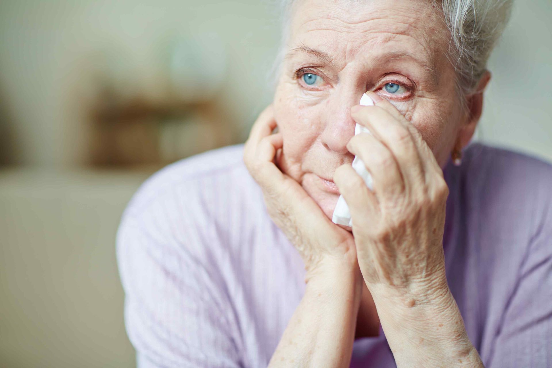 An elderly woman holding a tissue and feeling upset from nursing home negligence.  Clicking this picture takes you to Nursing Home Abuse and Neglect.