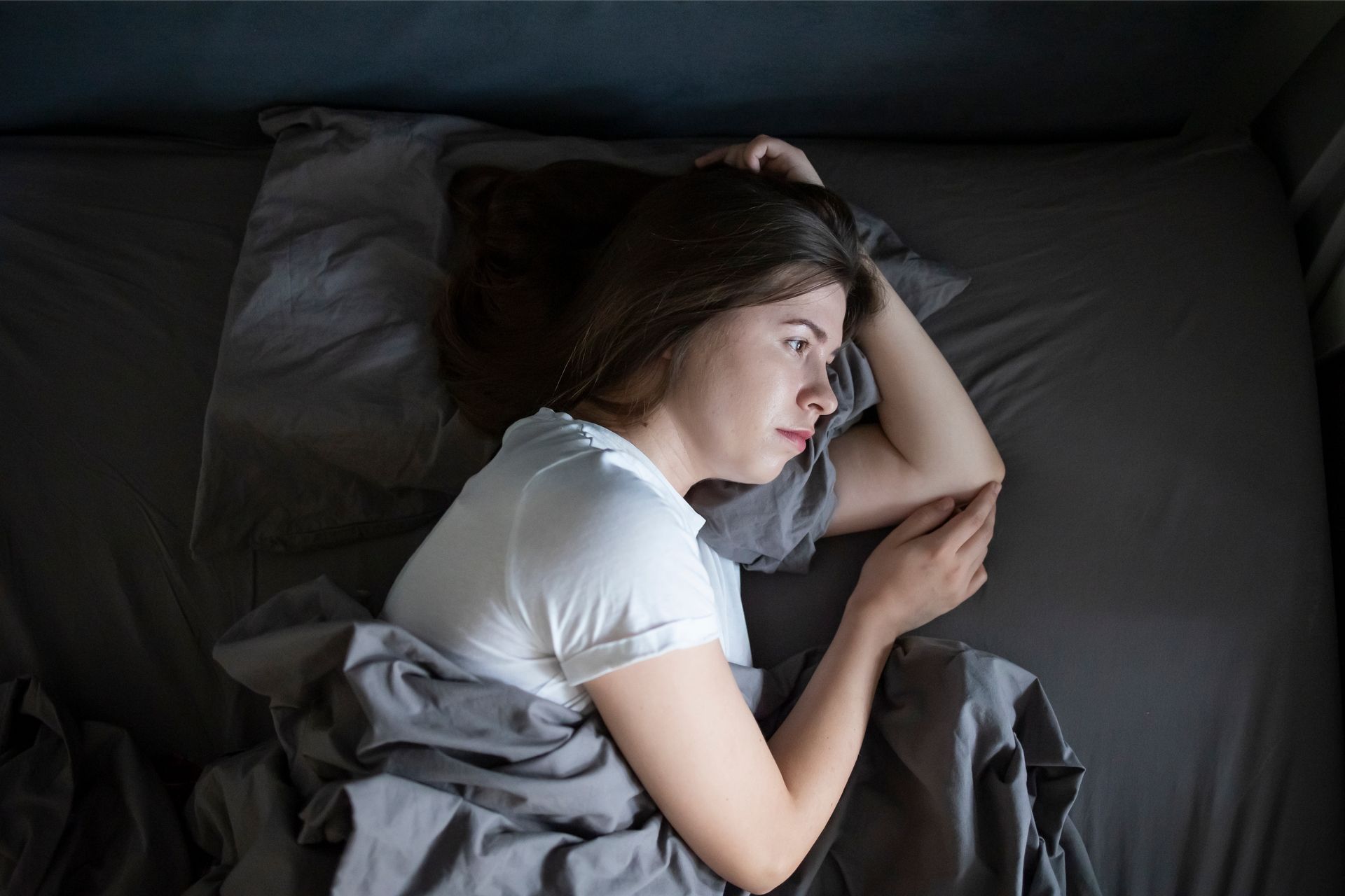 Woman lying awake in bed at night, showing insomnia, anxiety, and sleep difficulties often experienced after an accident or traumatic event.