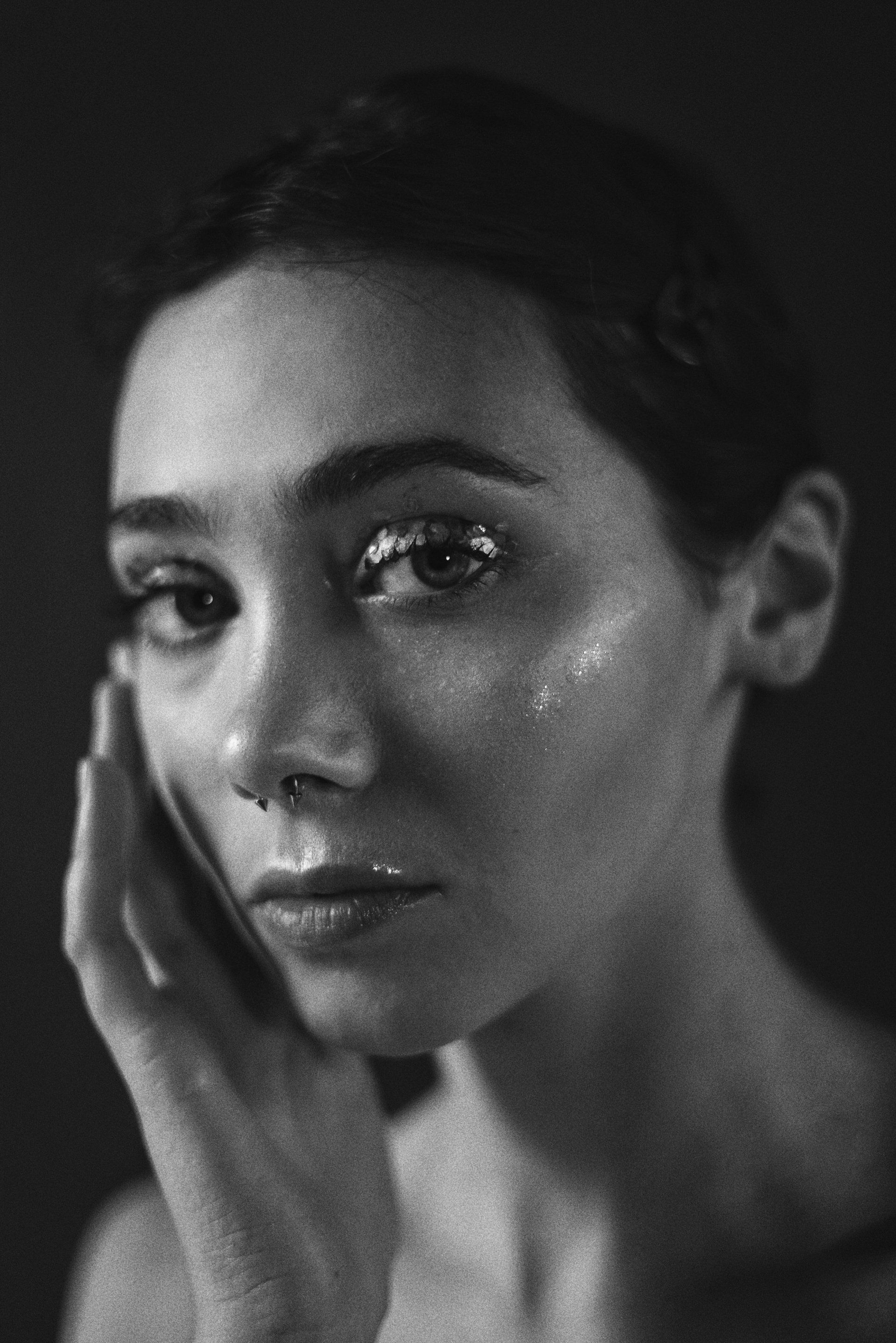 Uma foto em preto e branco de uma mulher aplicando loção no rosto.