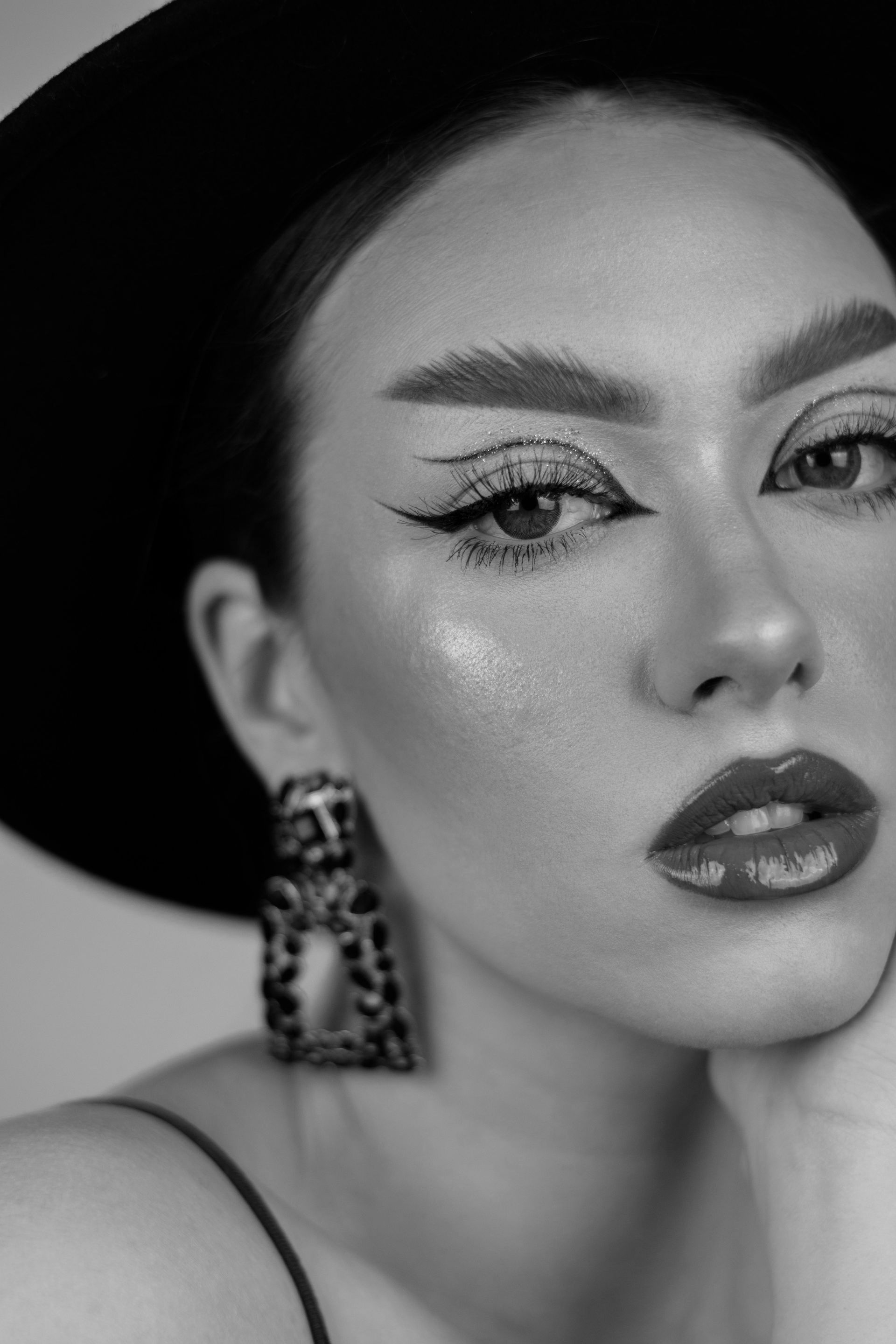 Uma foto em preto e branco de uma mulher usando chapéu e brincos.