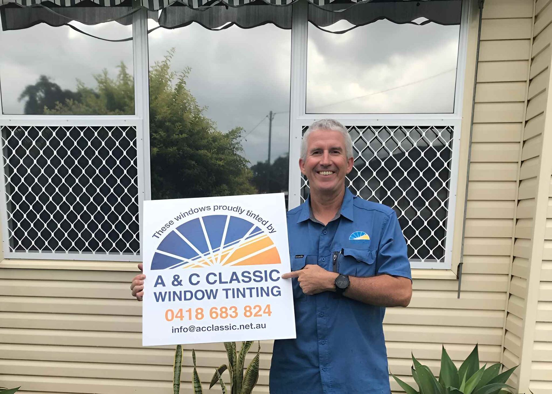 A Man Is Holding A Sign In Front Of A Window — A & C Classic Window Tinting In Maitland Vale, NSW