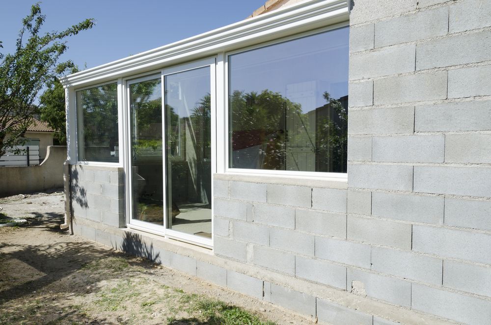 A Brick Building With A Sliding Glass Door And Windows — A & C Classic Window Tinting In Maitland Vale, NSW