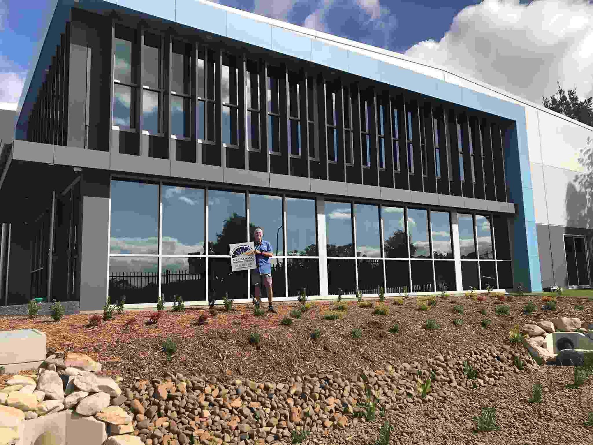 A Man Is Standing In Front Of A Large Building — A & C Classic Window Tinting In Maitland Vale, NSW