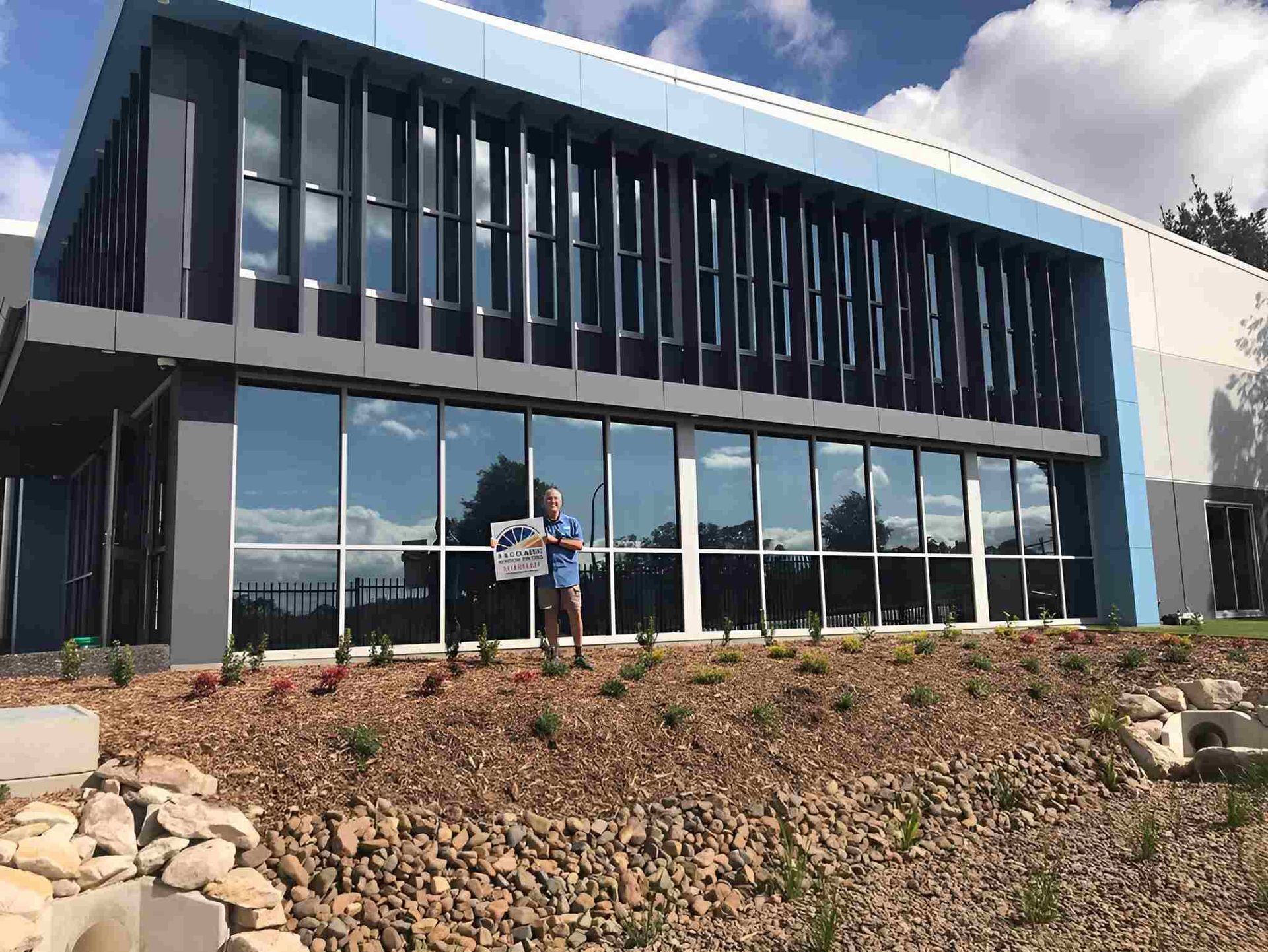 A Man Is Standing In Front Of A Large Building — A & C Classic Window Tinting In Maitland Vale, NSW