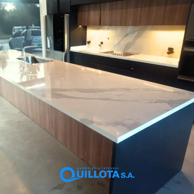 Isla de cocina moderna con encimera de mármol blanco y armarios de madera y negros en una exposición