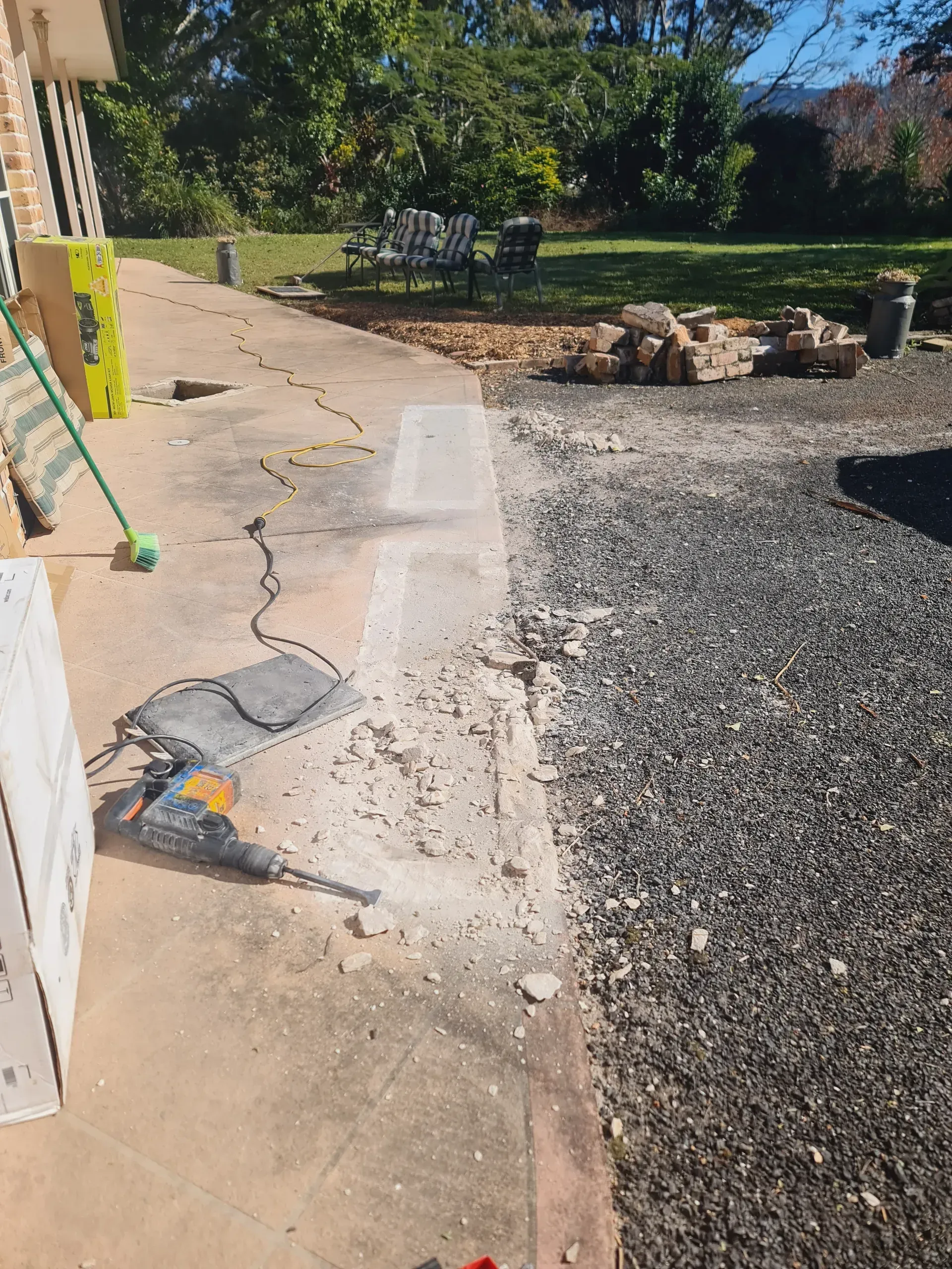 Concrete driveway leading to stairs and a brick building. An air conditioning unit is visible.