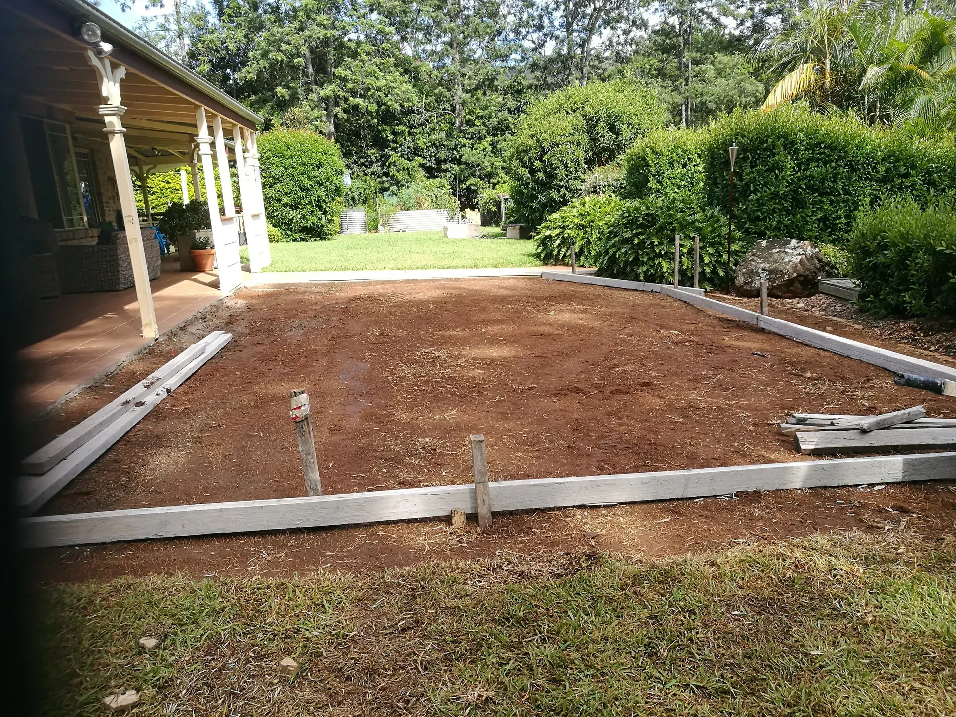 Dark grey paved driveway with a small boat on supports, bins, and a garage.