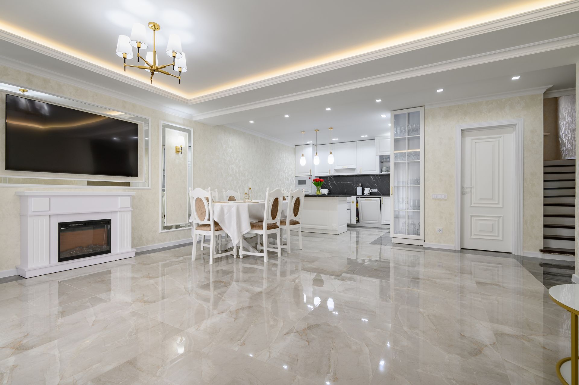 A living room with a fireplace , dining table , chairs , and polished marble flooring.