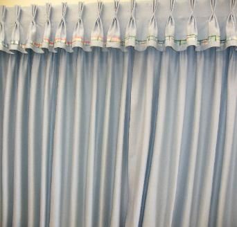 Light blue curtains with a pleated top, decorative trim, and vertical folds.