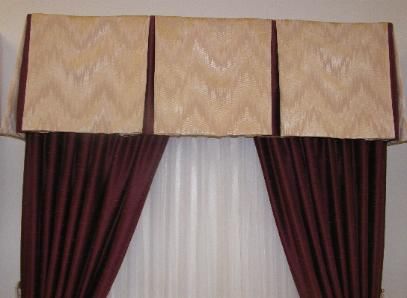 Window with beige valance above burgundy drapes and white sheer curtains.