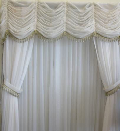 White sheer curtains with a gathered valance, trimmed with a beaded border.