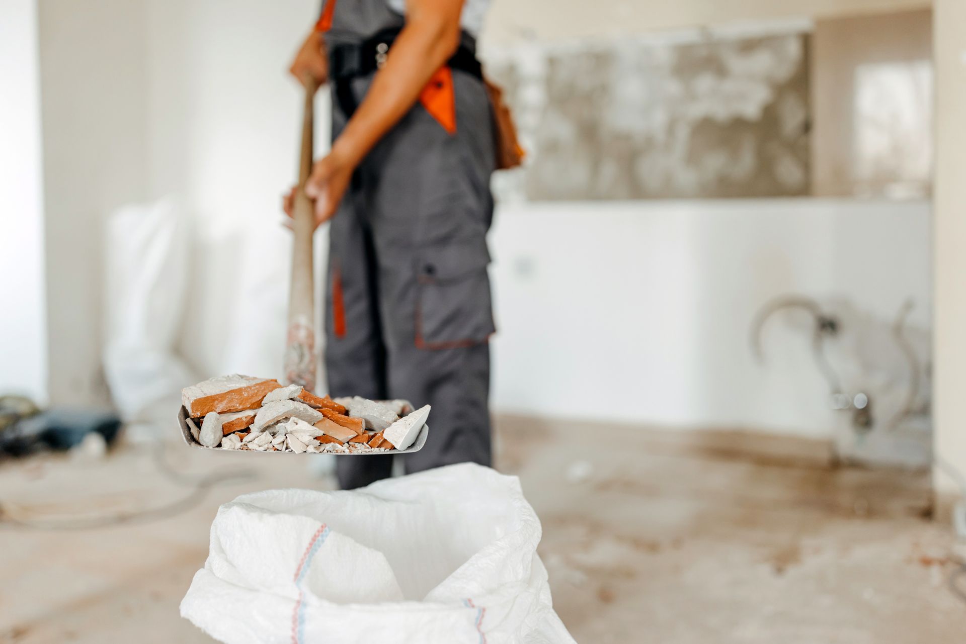 A man is holding a shovel and a bag of trash.