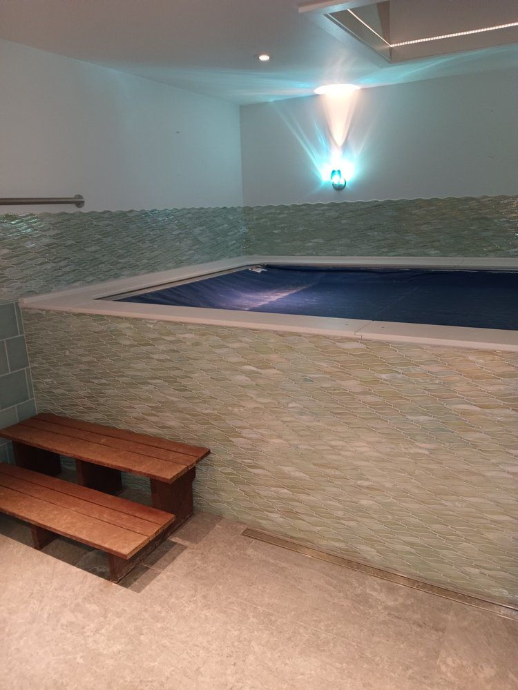 A large swimming pool in a room with wooden steps.