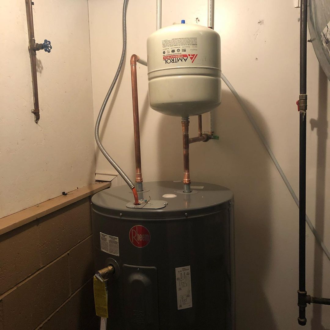 A water heater is sitting in a corner of a room.